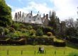St Fagans Caslte on a green hill with couple below with a pushchair