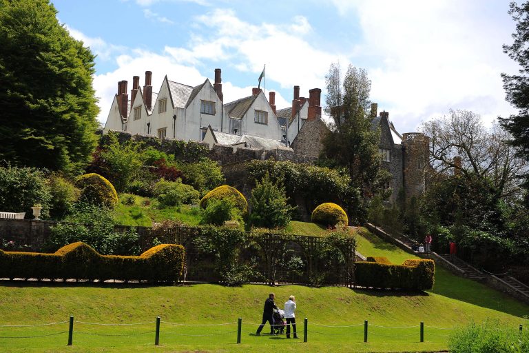 St Fagans Caslte on a green hill with couple below with a pushchair